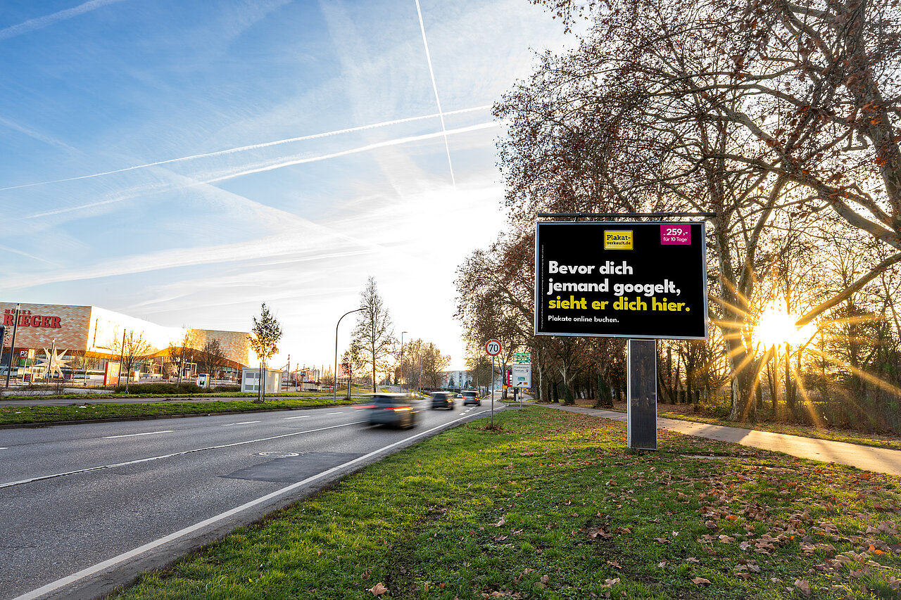 Großflächen am Straßenrand bei Sonnenuntergang mit Aufschrift: "Bevor dich jemand googelt, sieht er dich hier.". Im Hintergrund befindet sich das Möbelhaus Rieger in Heilbronn.