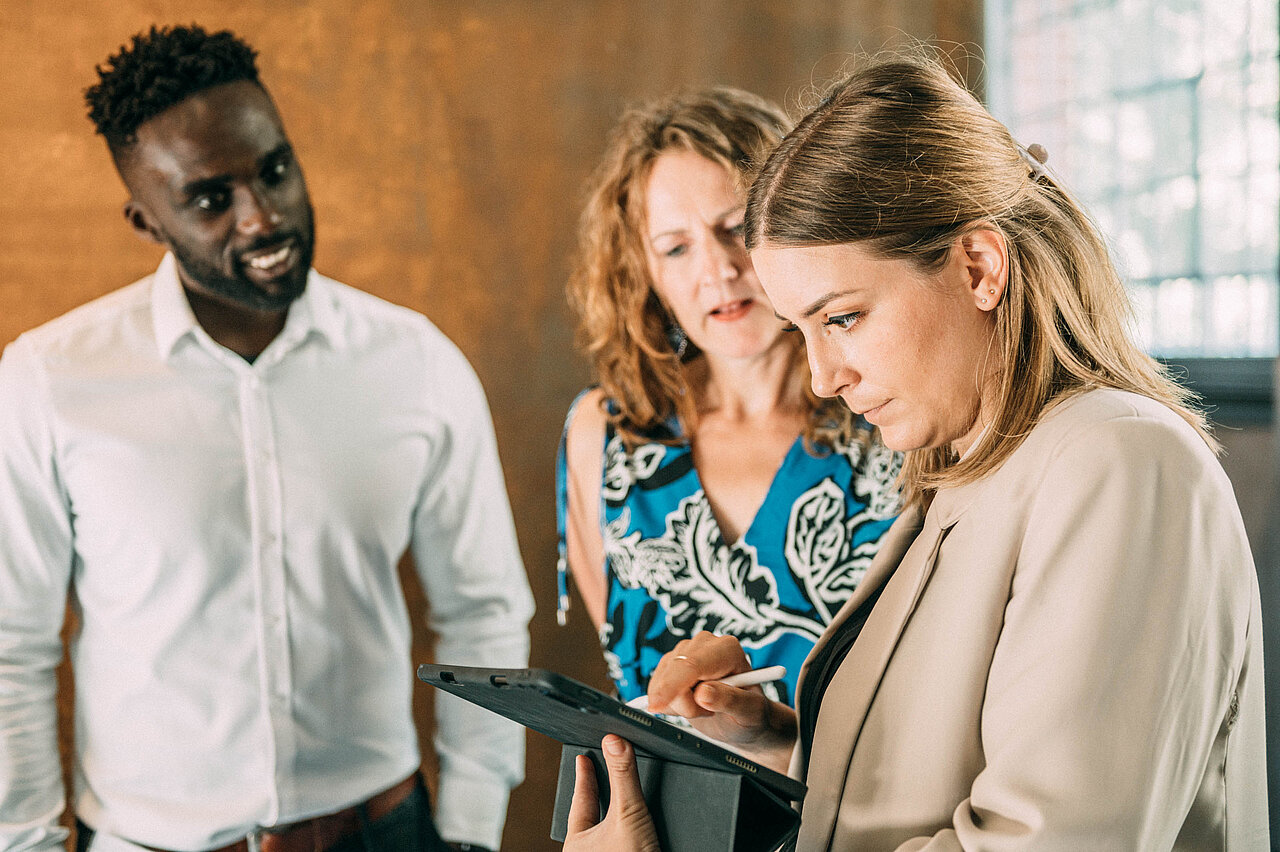 Teammitglieder von Plakat-verkauft.de besprechen Daten auf einem Tablet.