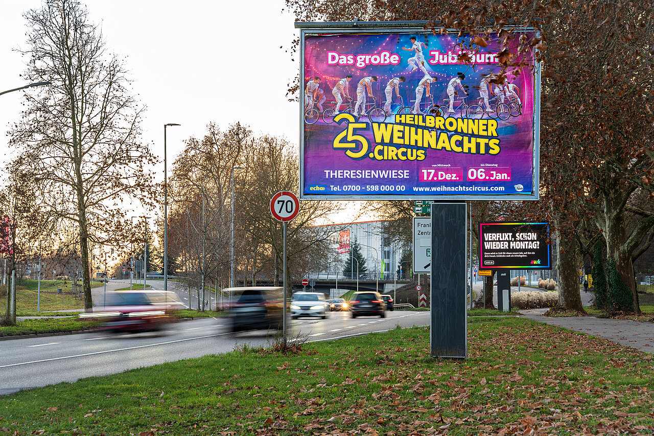 Großplakat an Schnellstraße mit Aufdruck des Heilbronner Weihnachtscircus. Sonnenuntergang im Hintergrund. 