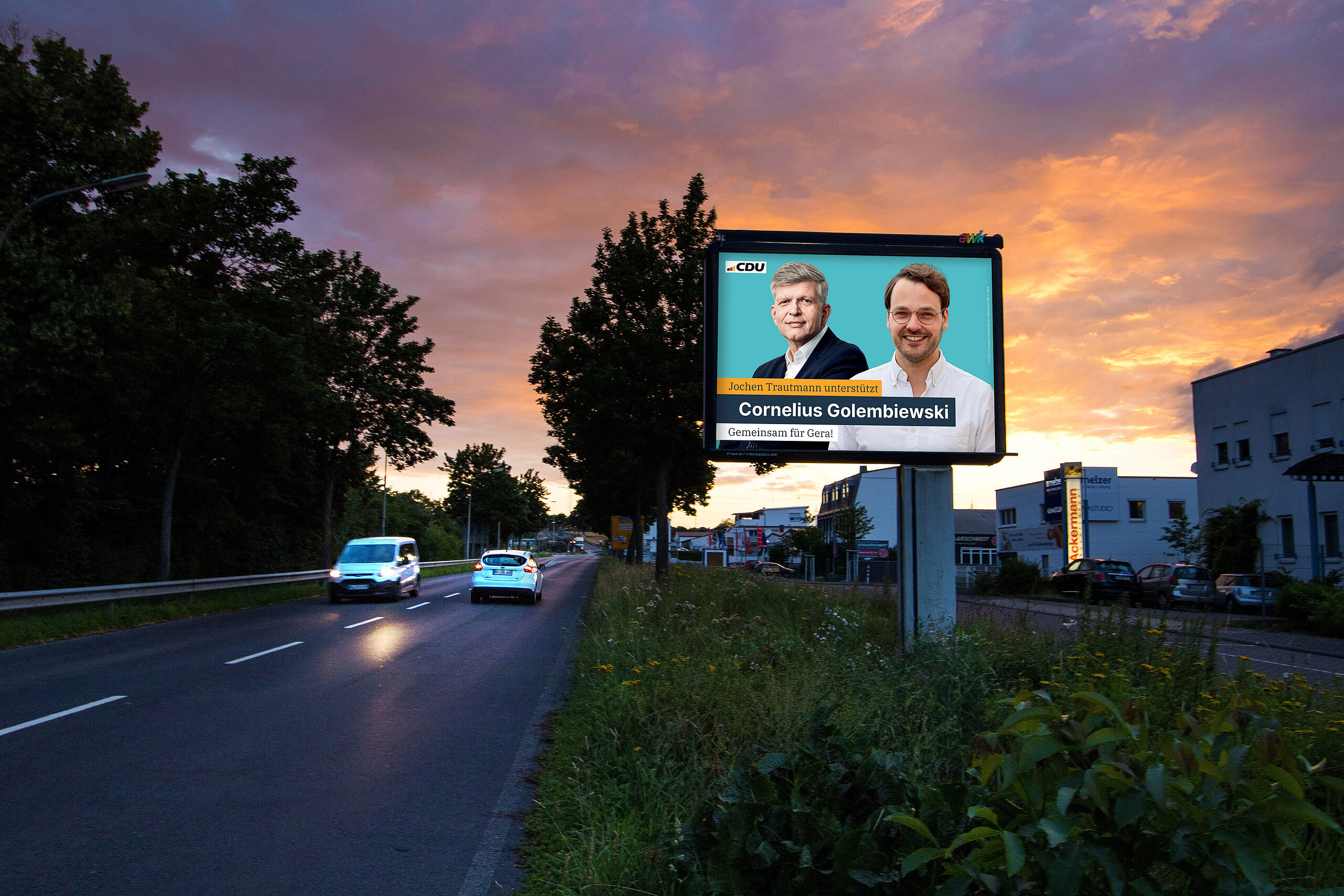 Plakatmotiv der CDU auf einem Großplakat an einer Straße bei Sonnenuntergang. Abgebildet sind Cornelius Golembiewski und Jochen Trautmann. Text: „Jochen Trautmann unterstützt Cornelius Golembiewski – Gemeinsam für Gera!“.