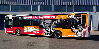 Buswerbung mit Hornbach-Motiv auf Normalbus vor der Lagerhalle der Stadtwerke Trier