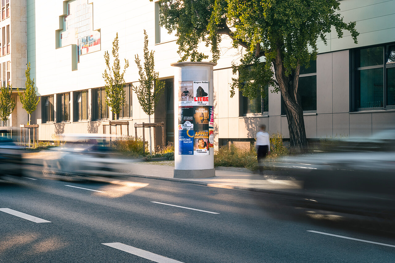 Medium Allgemeinstelle mit vielen Postern an befahrender Straße