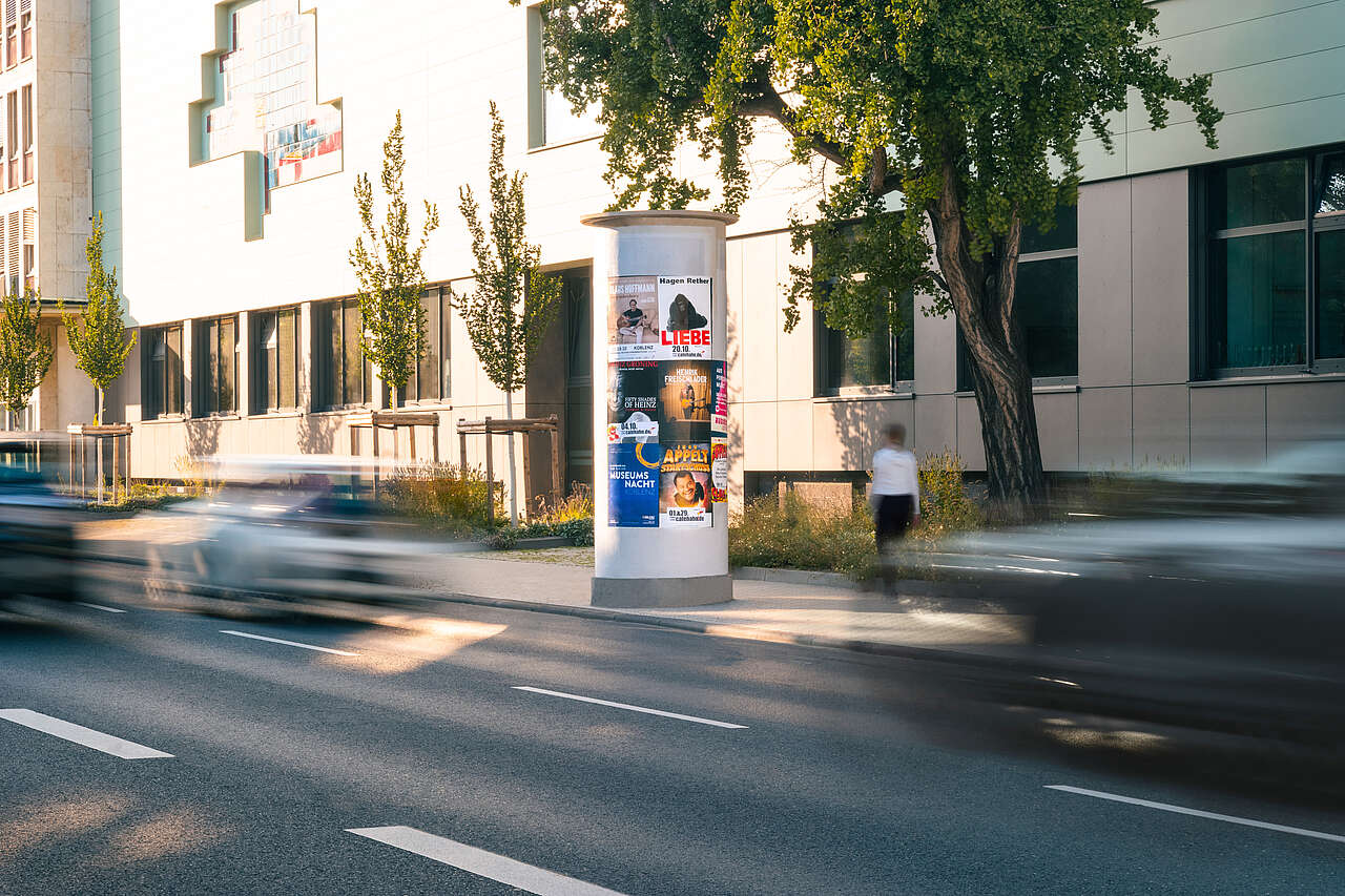 Medium Allgemeinstelle mit vielen Postern an befahrender Straße