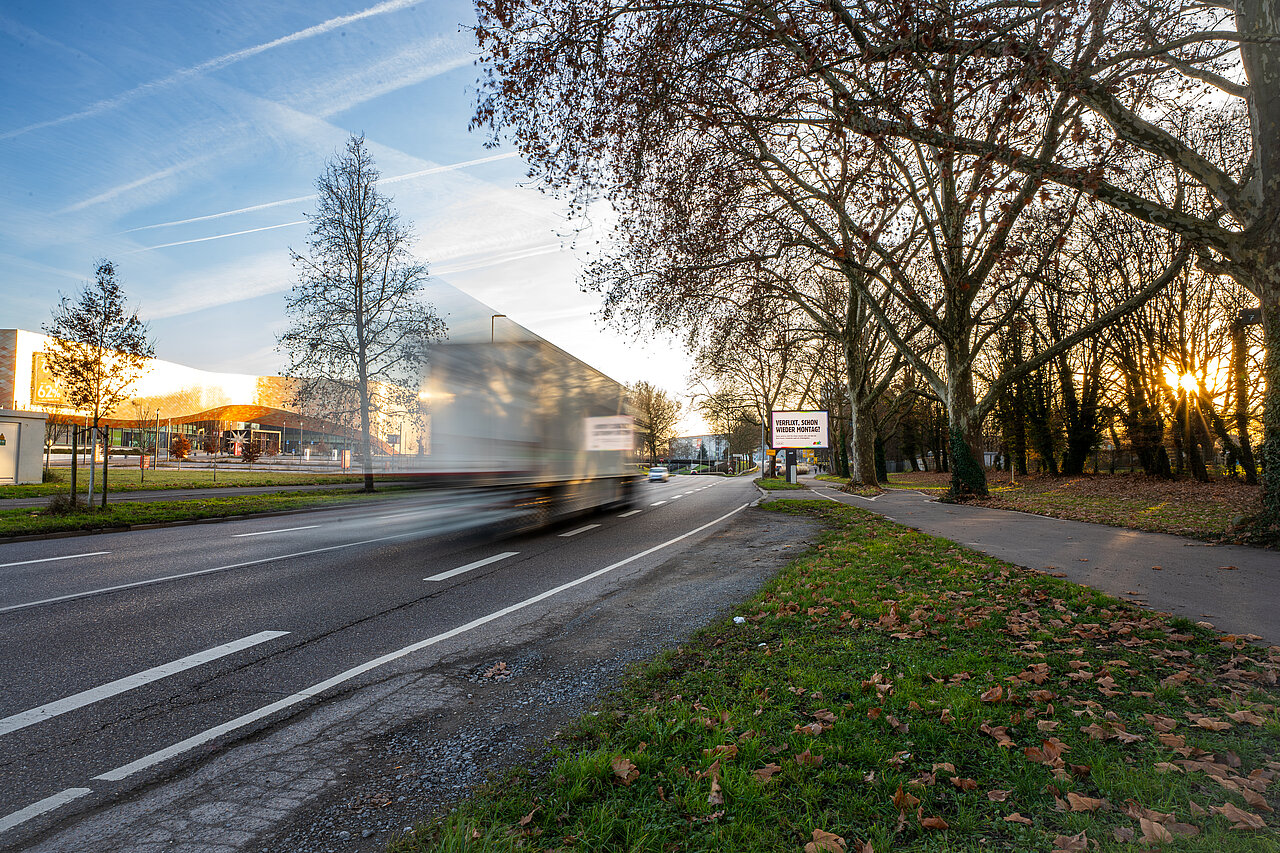 Großplakat an Schnellstraße mit vorbeifahrendem LKW. Im Hintergrund befindet sich das Möbelhaus Rieger in Heilbronn.