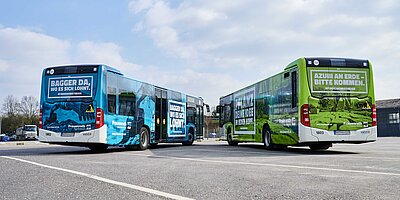Buswerbung von Frauenrath: Ganzgestaltung auf Bussen mit markanten Botschaften und einer auffälligen Farbgestaltung in Blau und Grün.