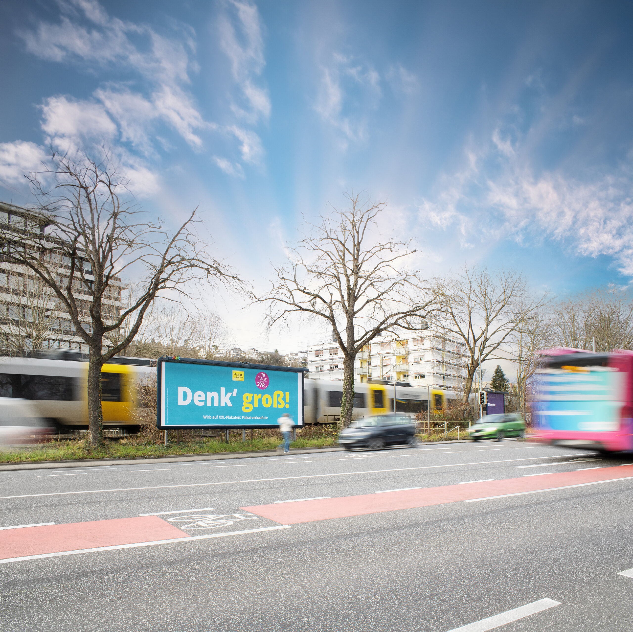 Megastar an einer stark befahrenen Straße, flankiert von Bus und Bahn. Die auffällige Platzierung garantiert hohe Sichtbarkeit im städtischen Raum.