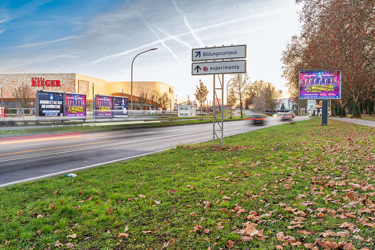 Mehrere Großflächen am Straßenrand bei Sonnenuntergang. Im Hintergrund befindet sich das Möbelhaus Rieger in Heilbronn.