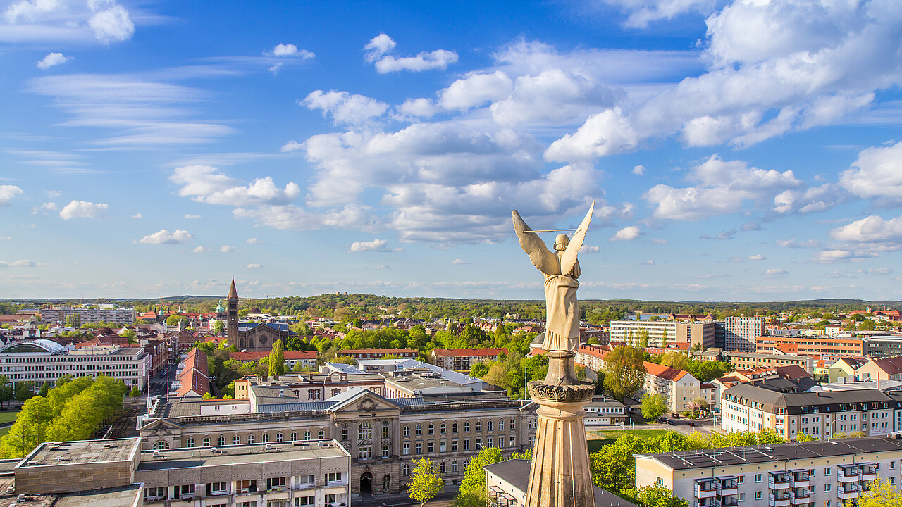 Blick über Potsdam mit Statue im Vordergrund und Altstadt bei blauem Himmel