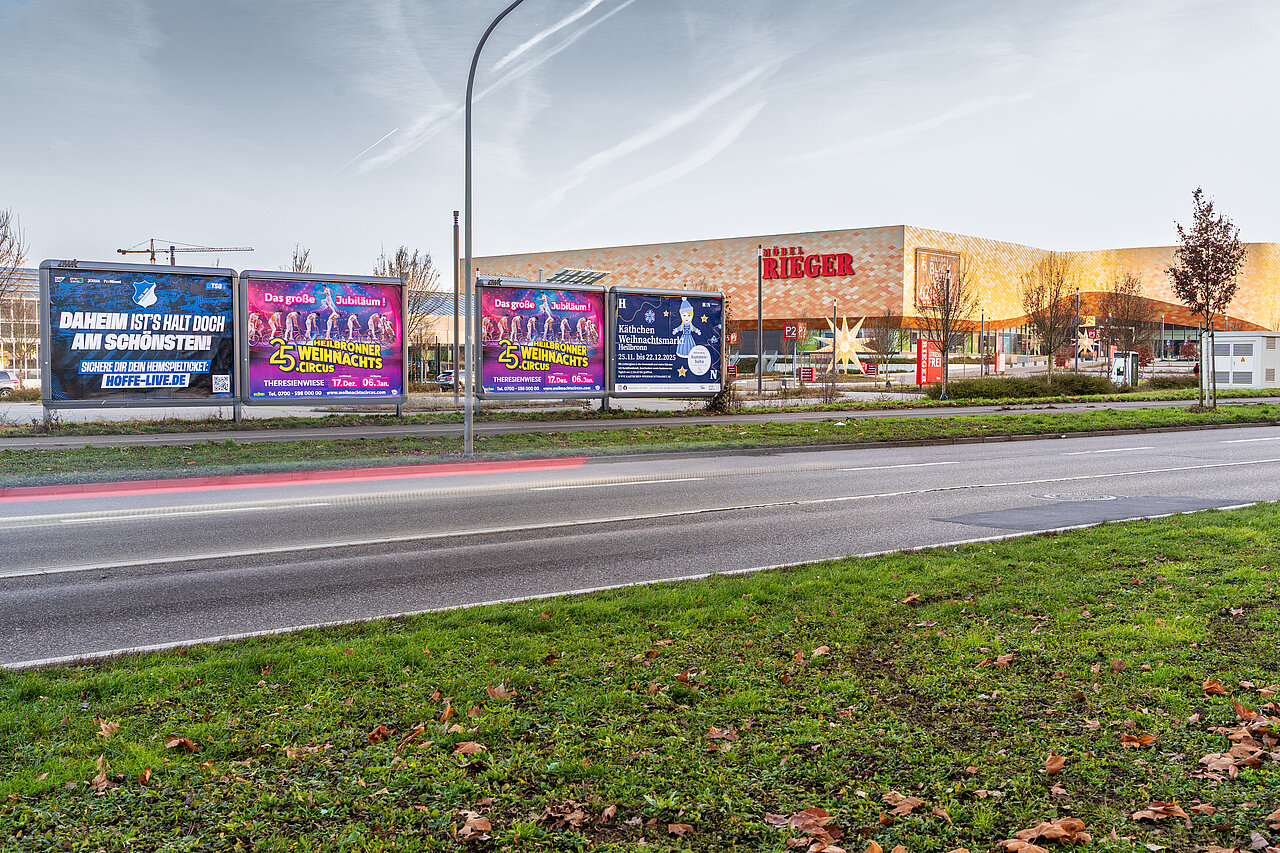 Mehrere Großflächen am Straßenrand am frühen Abend. Im Hintergrund befindet sich das Möbelhaus Rieger in Heilbronn.