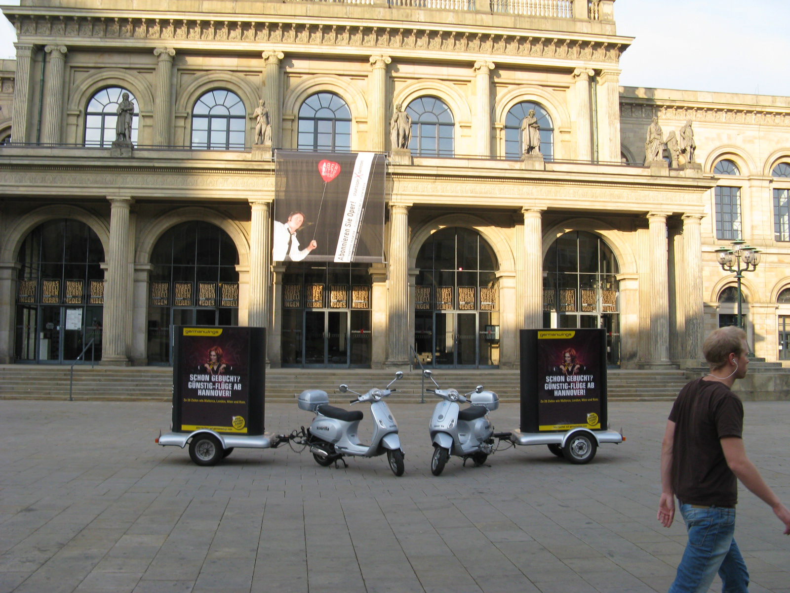 Zwei Motorroller mit mobilen Werbeanhängern vor einem historischen Gebäude, die aufmerksamkeitsstarke mobile Außenwerbung präsentieren.