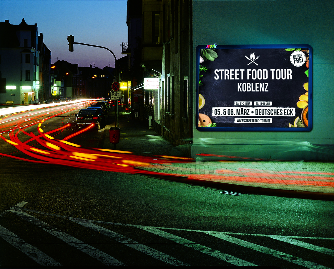 Beleuchtetet Großfläche an einer Hauswand montiert. Das Haus steht an einer stark befahrenen Kreuzung.